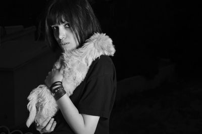 Portrait of woman looking away while standing against black background