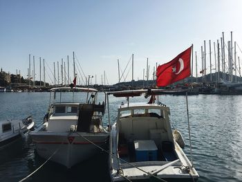 Boats moored at harbor against clear sky