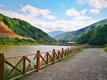 Scenic view of river by mountains against sky