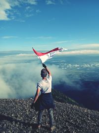 Rear view of man standing on sea against sky