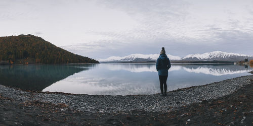 Young woman stands in front of lake tekapo and the southern alps