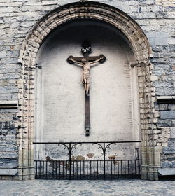 Jesus christ statue over cross against wall