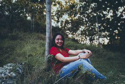 Portrait of smiling young woman sitting on field
