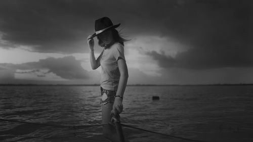 Woman standing at sea shore against sky