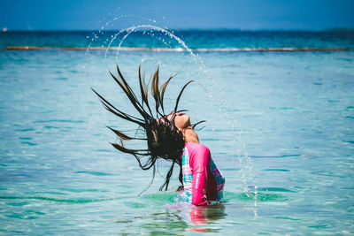 Full length of young woman splashing water