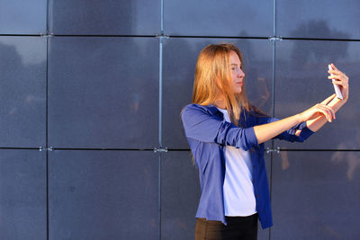 Full length of woman standing against wall