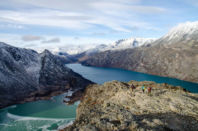Hikers tracking down a mountain ridge between two glacier lakes and snowcapped mountains