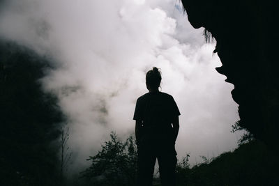 Rear view of silhouette man standing against cloudy sky