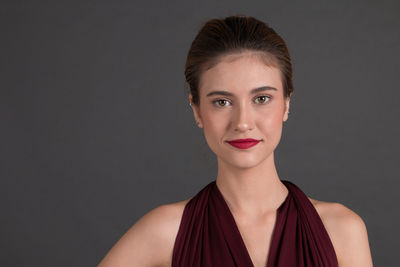 Close-up portrait of young woman against black background