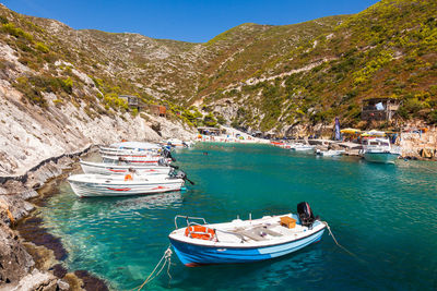 Boat moored on sea by mountain against sky