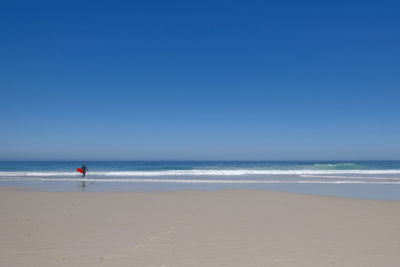 Scenic view of beach against clear blue sky