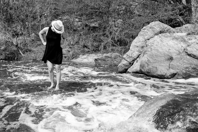 Full length of woman standing on rock by sea