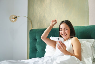 Portrait of young woman sitting on bed at home