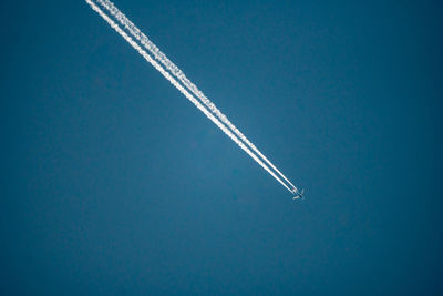 Low angle view of airplane flying against blue sky