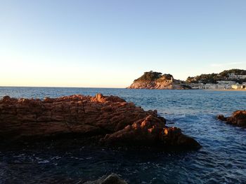 Rocks on beach against clear sky