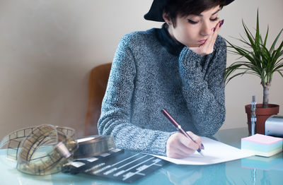 Female screenwriter writing on paper while sitting in office