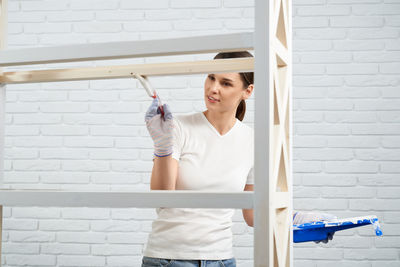 Young woman standing against white wall