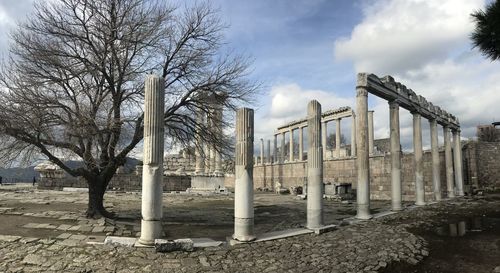 Built structure by bare trees against sky