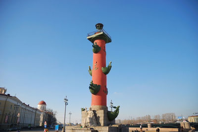 Low angle view of statue against buildings against clear blue sky