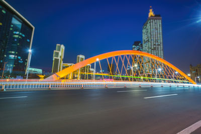 Light trails on bridge against buildings at night