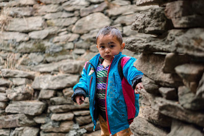 Boy standing against stone wall