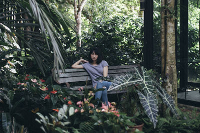 Woman sitting on plants in forest