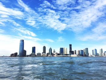 Sea by cityscape against sky