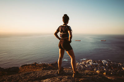 Full length of woman standing at beach against sky during sunset