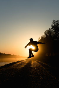 Silhouette man jumping against clear sky during sunset