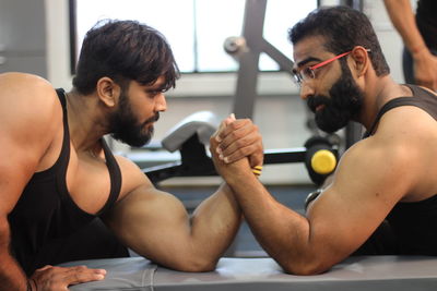 Male friends arm wrestling at gym