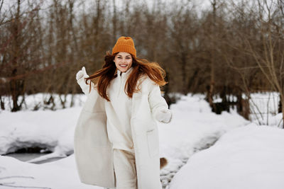 Young woman standing on snow covered field during winter