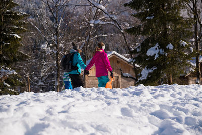 Mother with daughter and son walking on snow covered land in forest