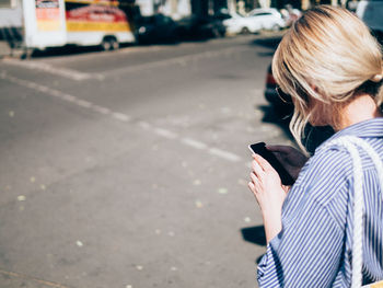 Rear view of woman using mobile phone on road