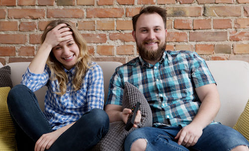 Smiling man and woman watching tv at home