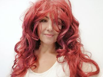 Close-up of smiling beautiful woman with redhead against white background