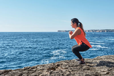 Fitness woman 40-50 years , in sports set training weights gym exercises, in front of the water	