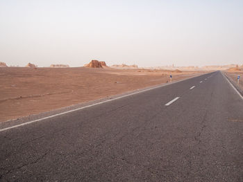 Road by desert against clear sky