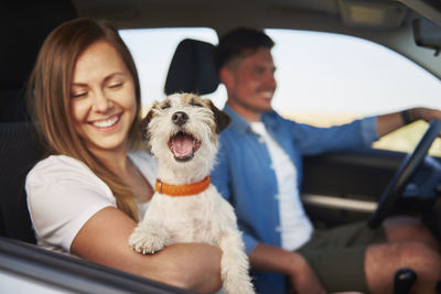 Smiling couple with dog in car