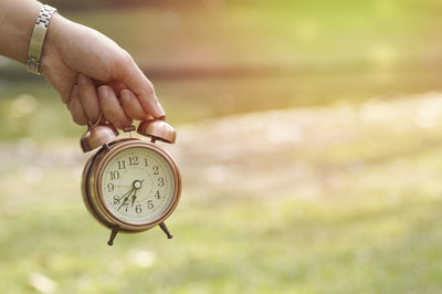 Close-up of hand holding alarm clock outdoors