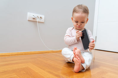 Portrait of boy sitting on hardwood floor at home