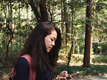 Young woman looking at phone in forest