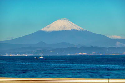 Scenic view of sea and snowcapped mountain against sky