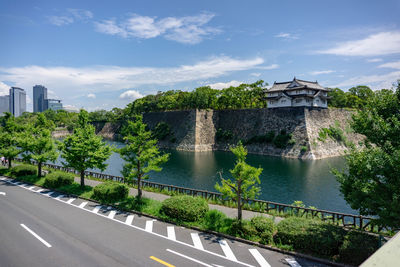 Bridge over river by buildings against sky