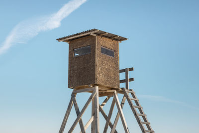 Low angle view of raised hide against clear blue sky