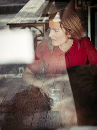 Woman looking down while sitting on table