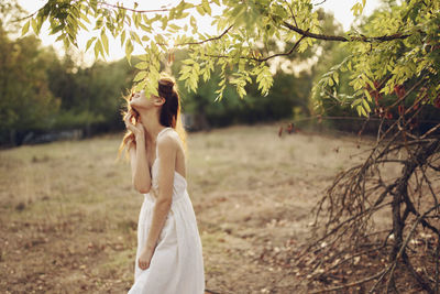 Woman standing on field by tree