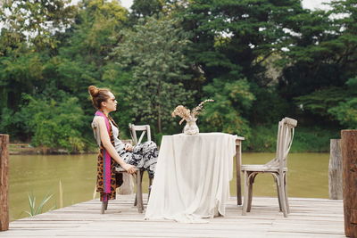 Side view of woman standing against trees