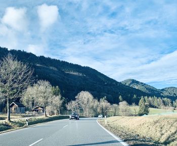 Road by trees against sky