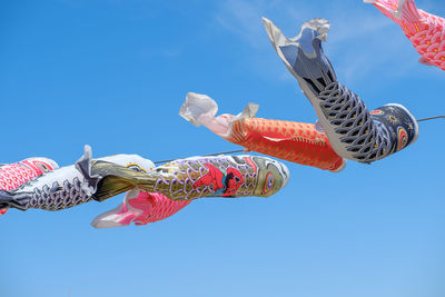 Low angle view of fish decorations hanging against sky