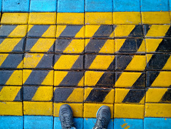 Low section of man standing on yellow road